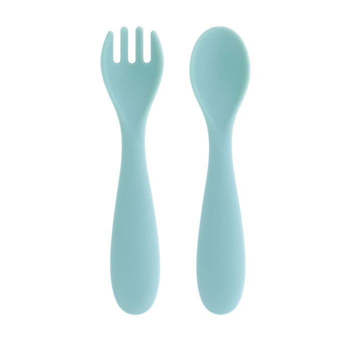 The Nuby Toddler Feeding Set | Muted features two light blue plastic utensils—a fork with three wide tines and a spoon—both with rounded, ergonomic handles for easy self-feeding, displayed side by side on a white background.