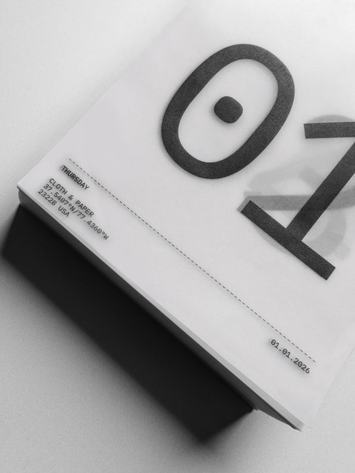 Close up of the bottom of the 2026 Today Tear Off Pad showing the vellum pages with large numerical date and footer text with the day of the week, full numerical date, Cloth & Paper, and map coordinates.