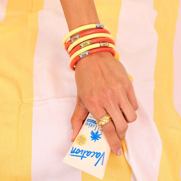 a hand with bracelets and a package of cream
