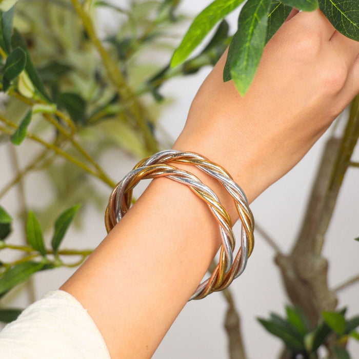 Trilogy All Weather Bangle® worn on a hand, showcasing gold, silver, and champagne intertwined in elegance.