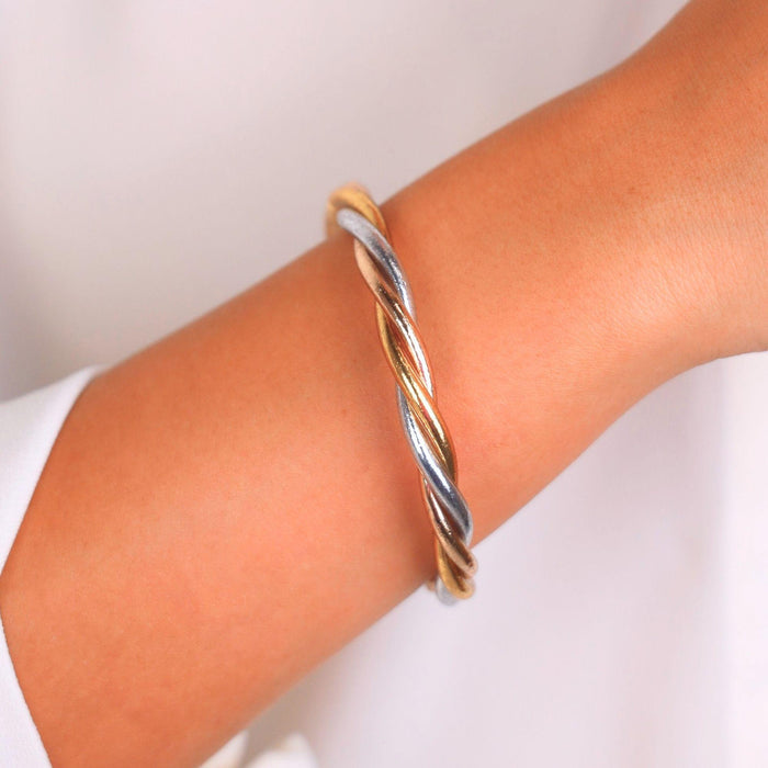 Trilogy All Weather Bangle® showcased on a wrist, featuring a twist of gold, silver, and champagne hues.